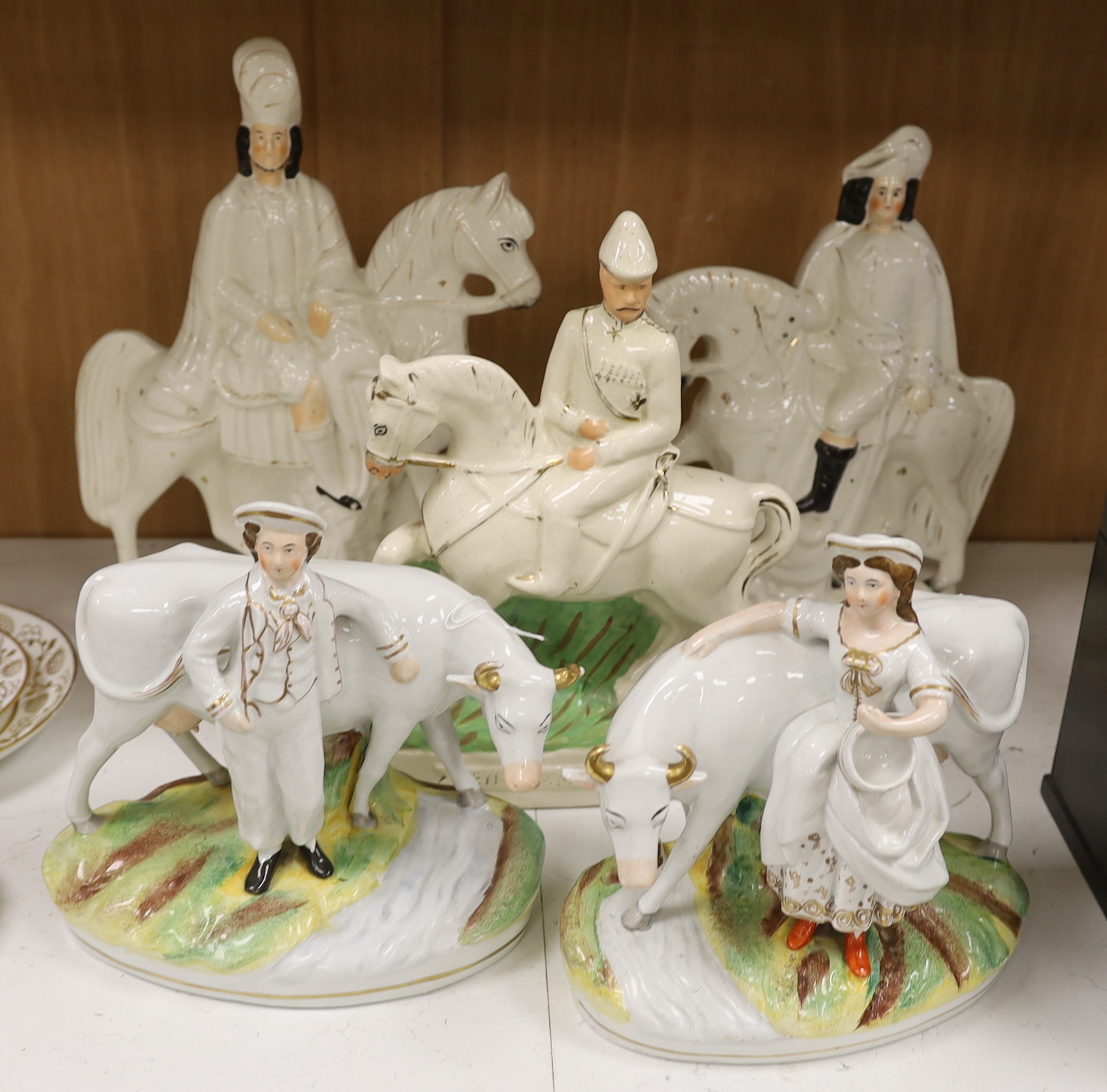 A pair of Staffordshire cow herder figure groups and three Staffordshire equestrian groups, tallest 38cm high